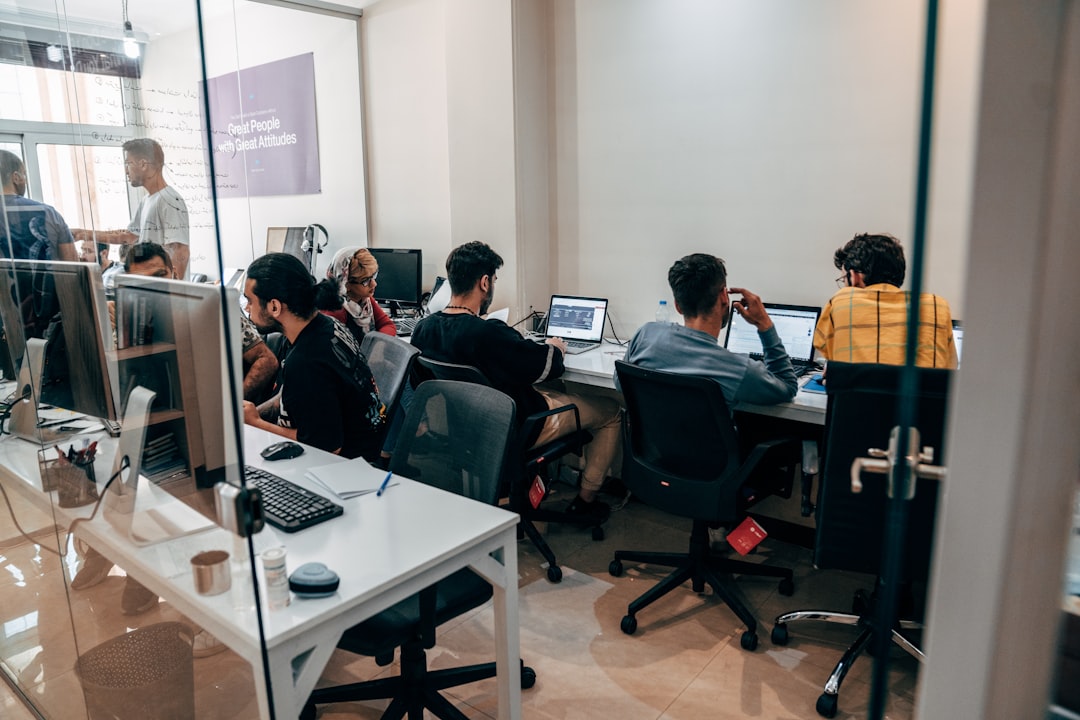 An engineering team reviewing a laptop-based workflow diagram in a bright office