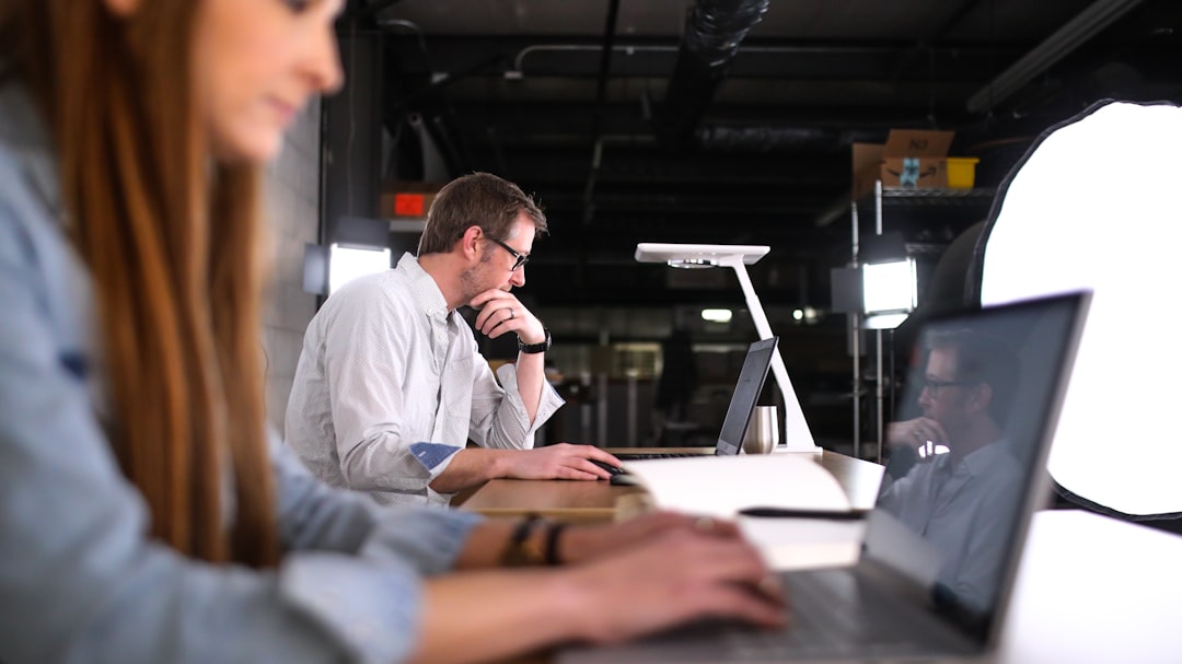 Two people reviewing a visual AI workflow on a laptop in a coworking office