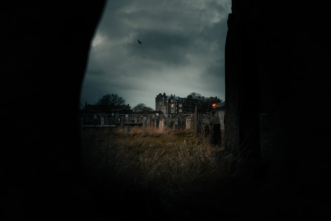Dark medieval ruins scene at dusk with a lone cloaked hero