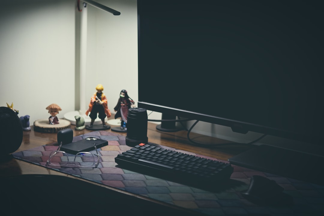 Wide gaming desk view with a PC monitor showing a Gears of War style action scene