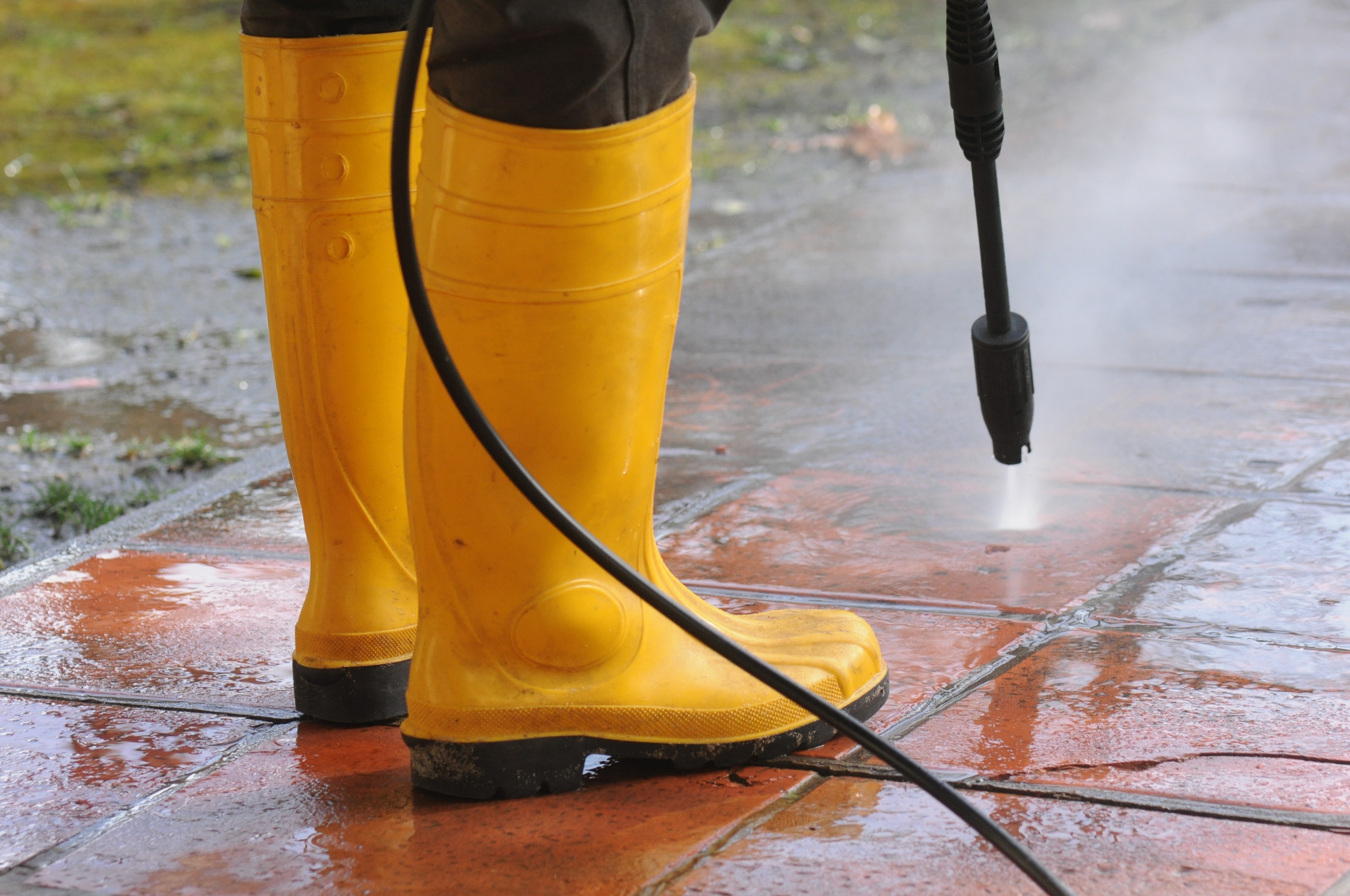 Compact cordless pressure washer used on a car wheel and patio furniture outdoors