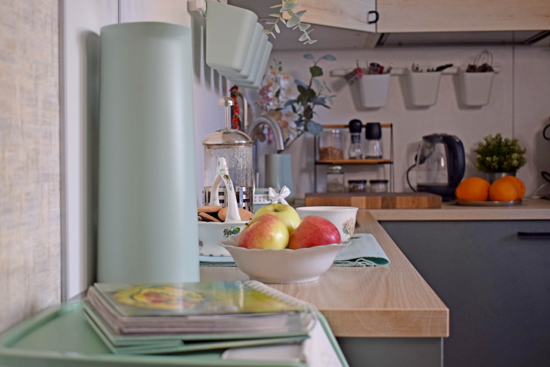 A modern countertop setup with a kettle, milk steamer, and serving mugs for tea, coffee, and cocoa