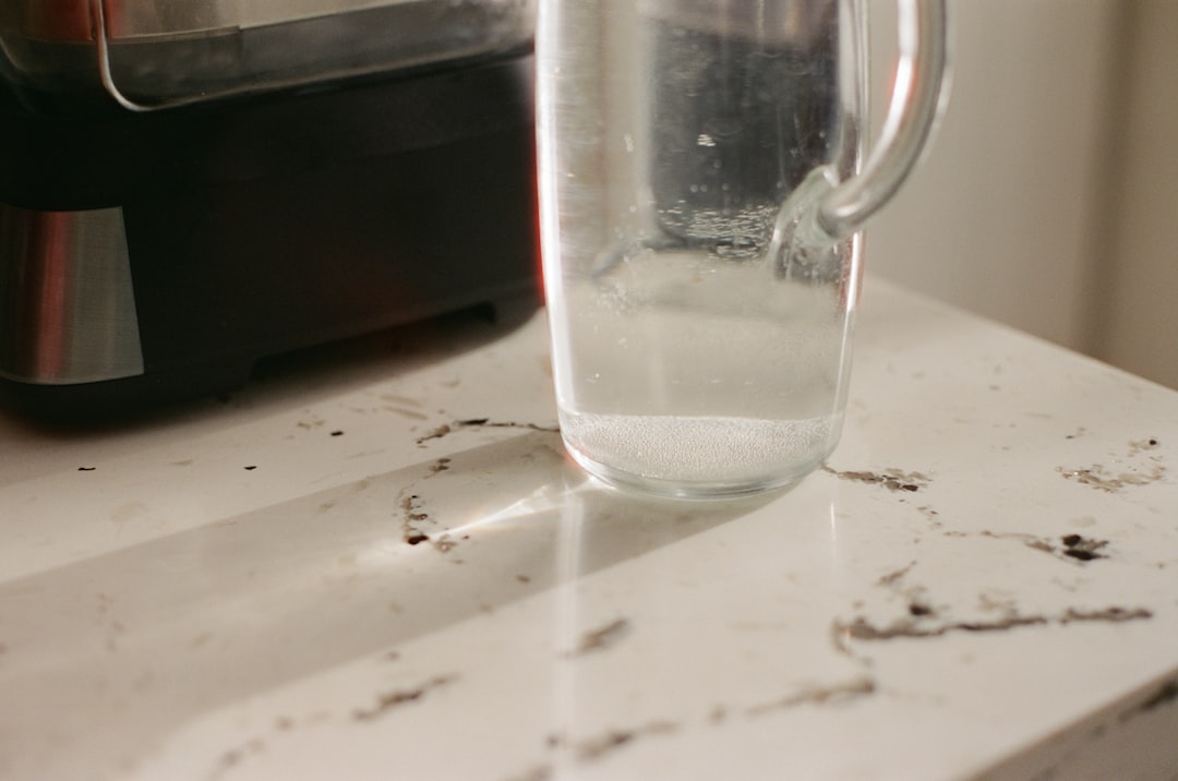 Detachable milk frother pitcher beside cocoa, matcha, and iced latte mugs on a kitchen counter.