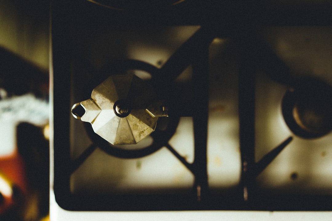 A clean stainless steel kettle beside a tea mug and warm milk steamer