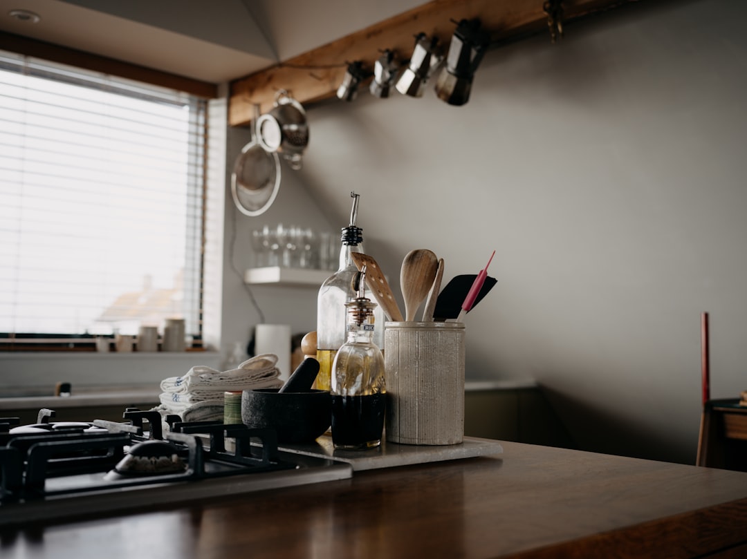 Small kitchen counter with one milk frother, one kettle, and a chocolate pot lined up for espresso and hot cocoa service.
