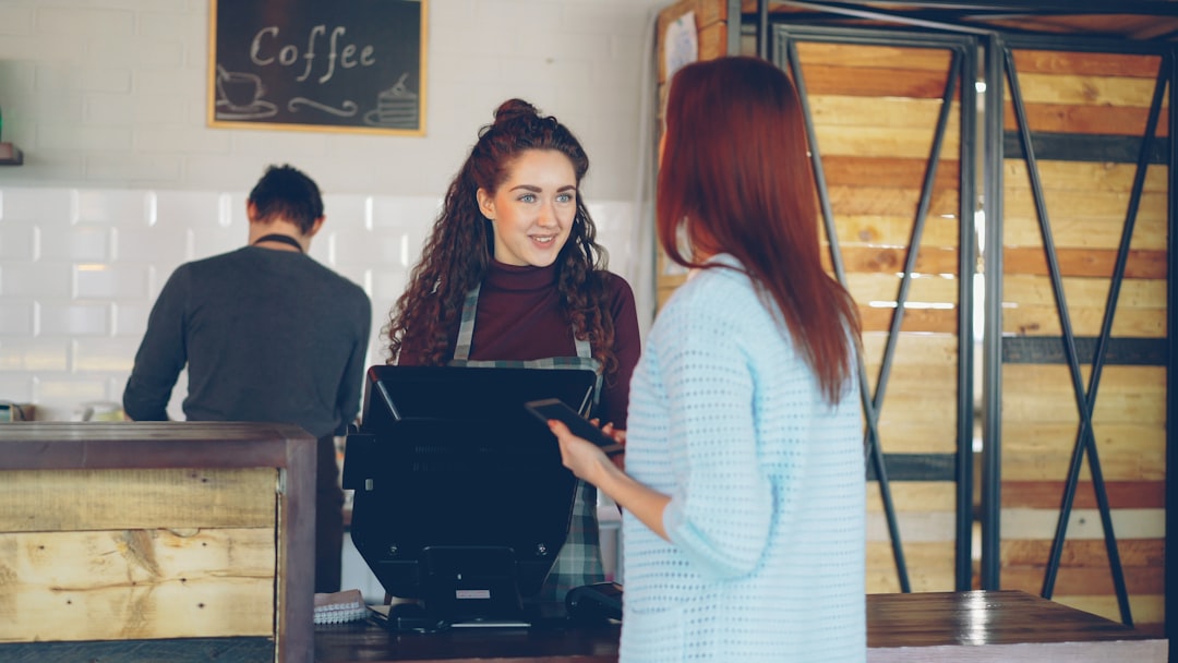 Shop staff using a desk checklist while reviewing a payment alert